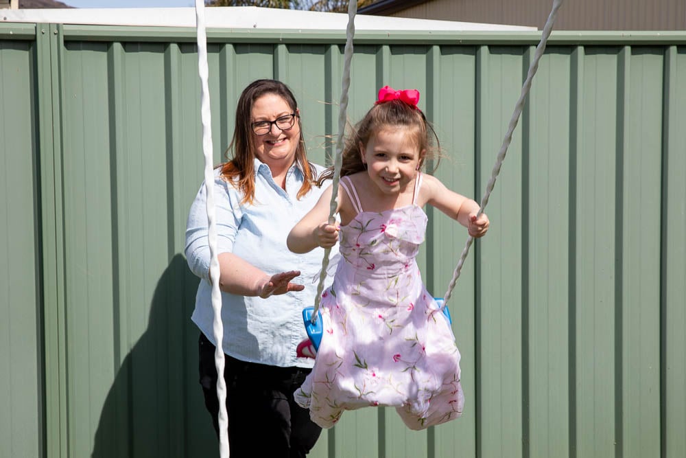 A single mother pushing her daughter on a swing