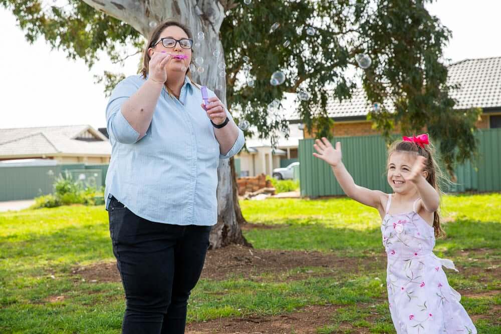 A single mum with her daughter blowing bubbles outdoors