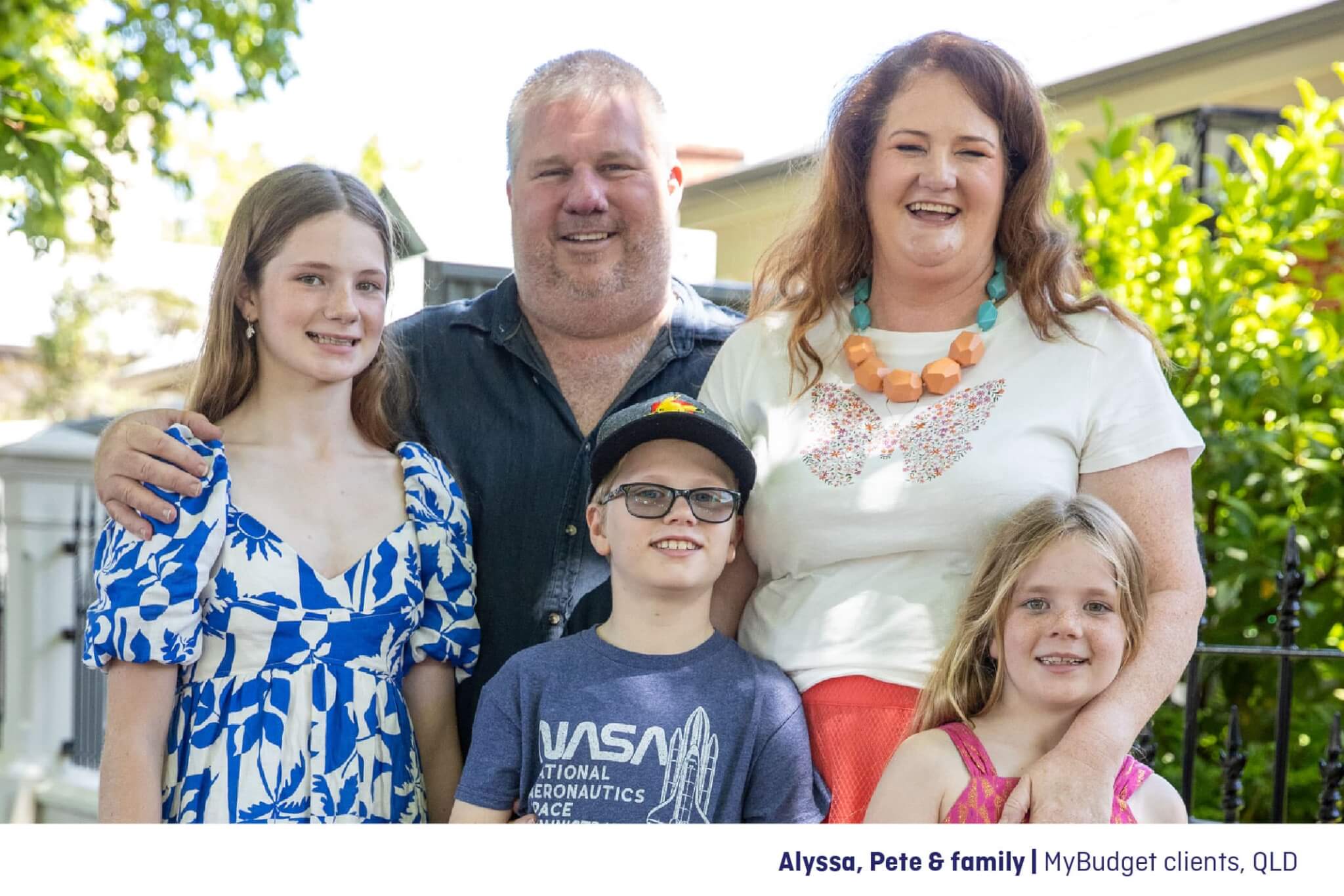 Alyssa and Pete, MyBudget clients, stand happily with their children outside their home, feeling relieved and in control of their finances after joining MyBudget and achieving financial peace of mind.