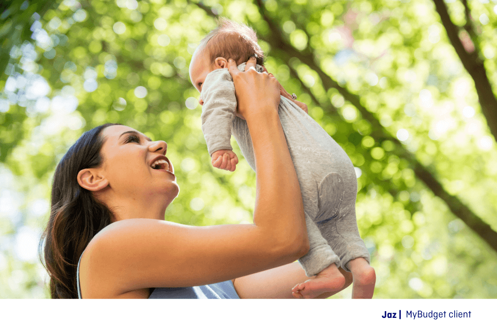 Jaz, a MyBudget client, holding her newborn baby in a sunny park. Mother’s Day is made simple with our top gift idea list for every budget.