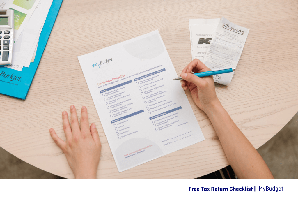 A close up image of a MyBudget's clients hands filling out the free tax return checklist form for tax time 2025 Australia.