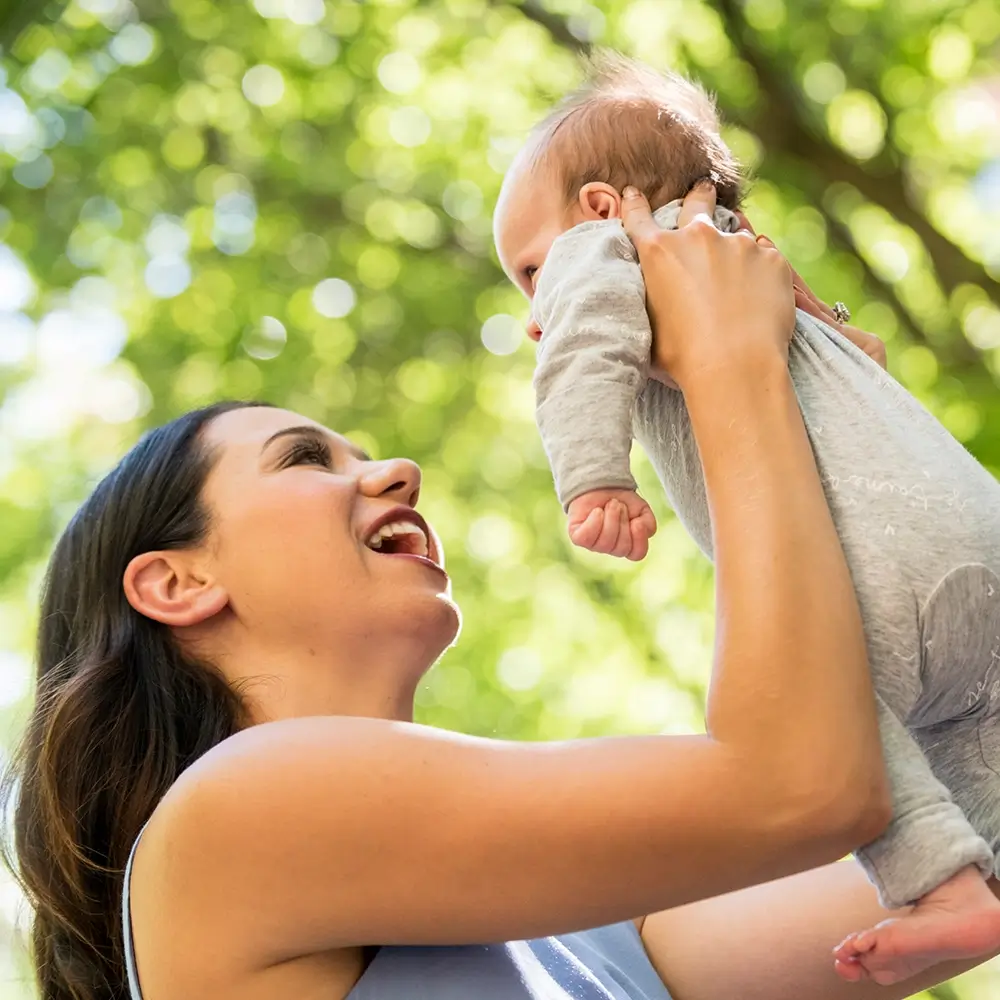 MyBudget client Jaz holding her newborn outdoors, representing Australian parents preparing and budgeting for a new baby.