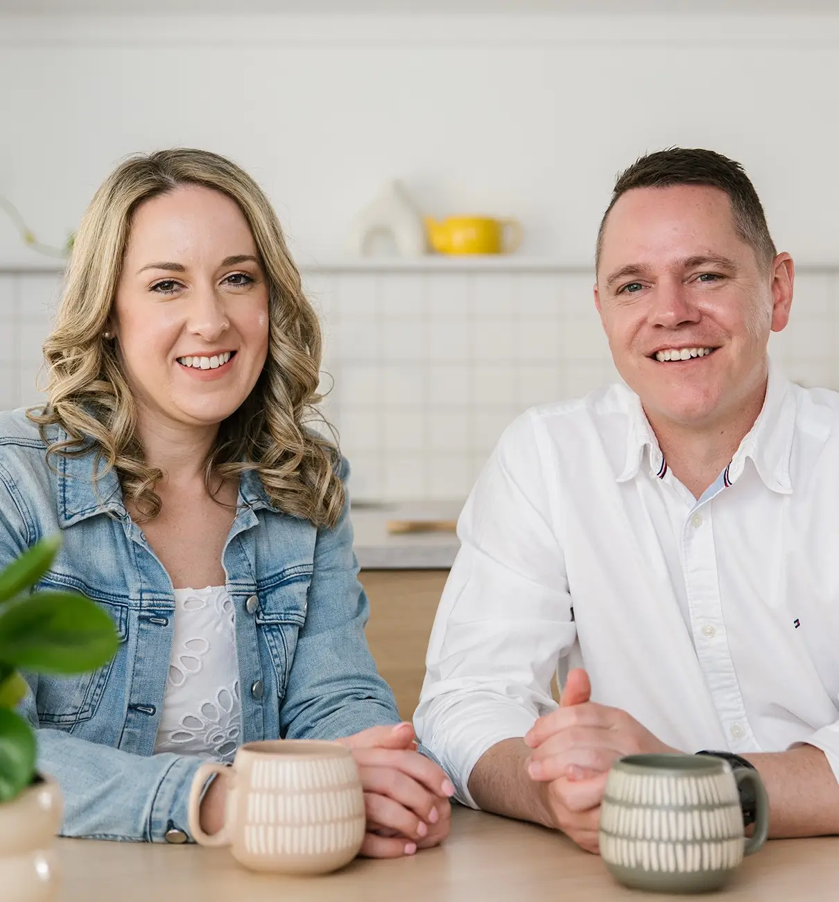 MyBudget clients Adam and Erin celebrate success at the dining table after achieving financial goals and debt solutions in Australia.