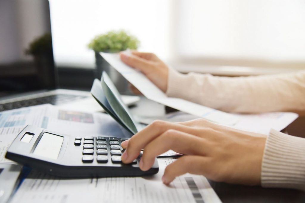 A hand with fingers over a black calculator whilst looking at papers in their right - what is bankruptcy?