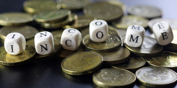 Six dice in a row sitting on a stack of gold coins that spell out the word income: Budgeting for Christmas