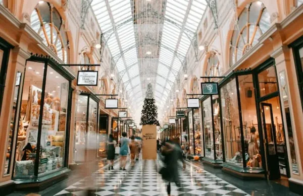 This image shows a decorated shopping arcade bustling with people, featuring a Christmas tree at its centre, suggesting a lively and festive shopping environment during the holiday season in Australia.
