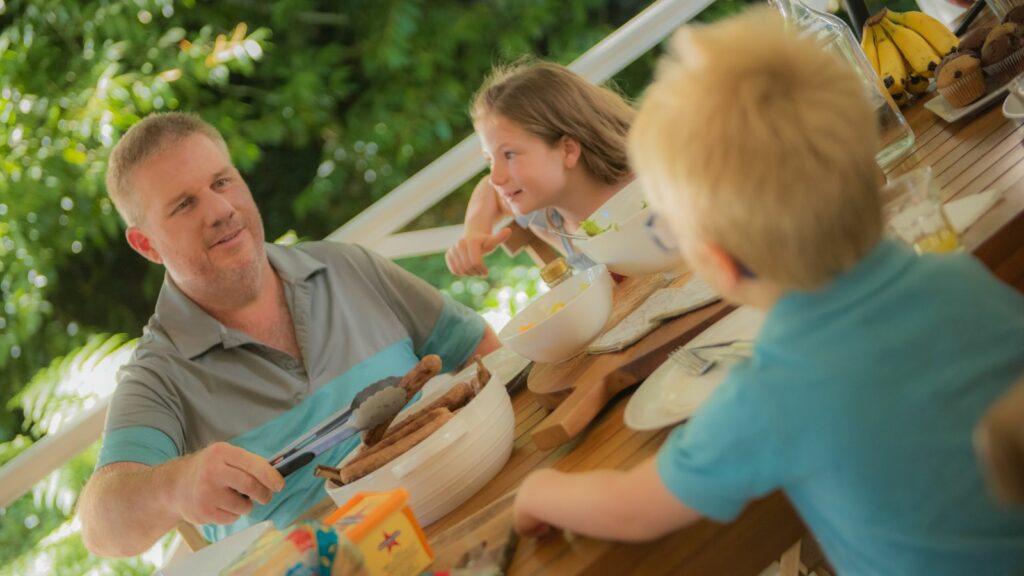 Family sitting around a table eating lunch outside - federal budget Australia