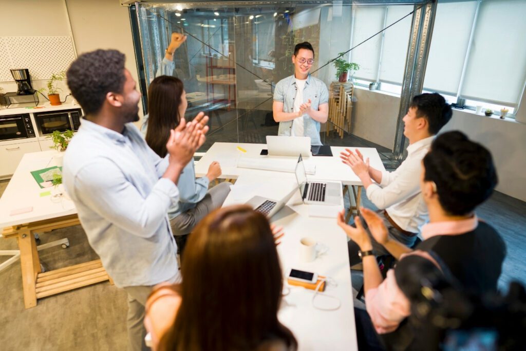 Six workers in the office standing around a table wearing affordable workwear