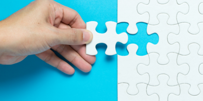 A hand going to place the final jigsaw piece on a white jigsaw puzzle: Stocking fillers for kids.