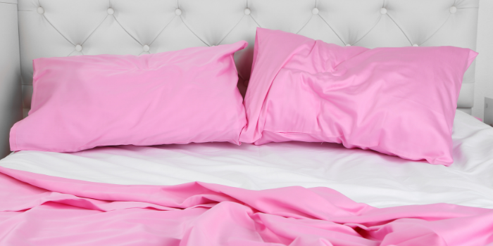 Two pink silk pillowcases with a pink quilt cover and white sheets on a bed: Stocking fillers for women.
