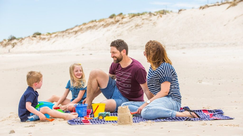 A family on the beach enjoying quality kids school holiday activities.