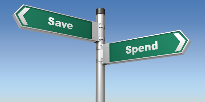 A street sign with a green arrow pointing left that says "Save" and a green arrow pointing right that says "Spend".