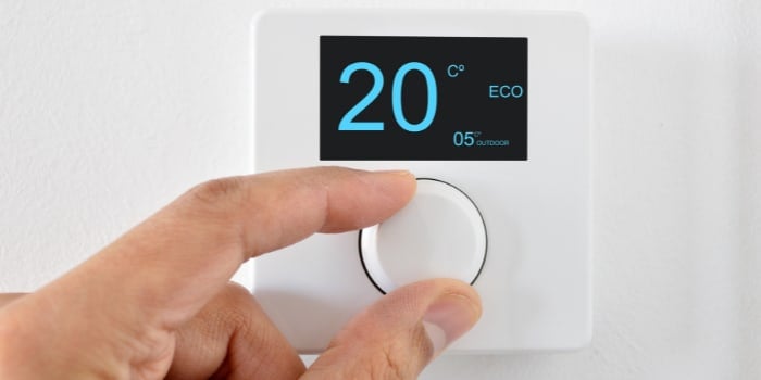 Try these energy saving tips: Set your thermostat to an efficient setting, like this person turning the dial to 20°C on ECO mode.