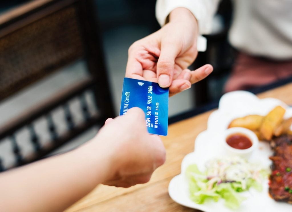 A person passing their credit card to a waiter to pay for their meal