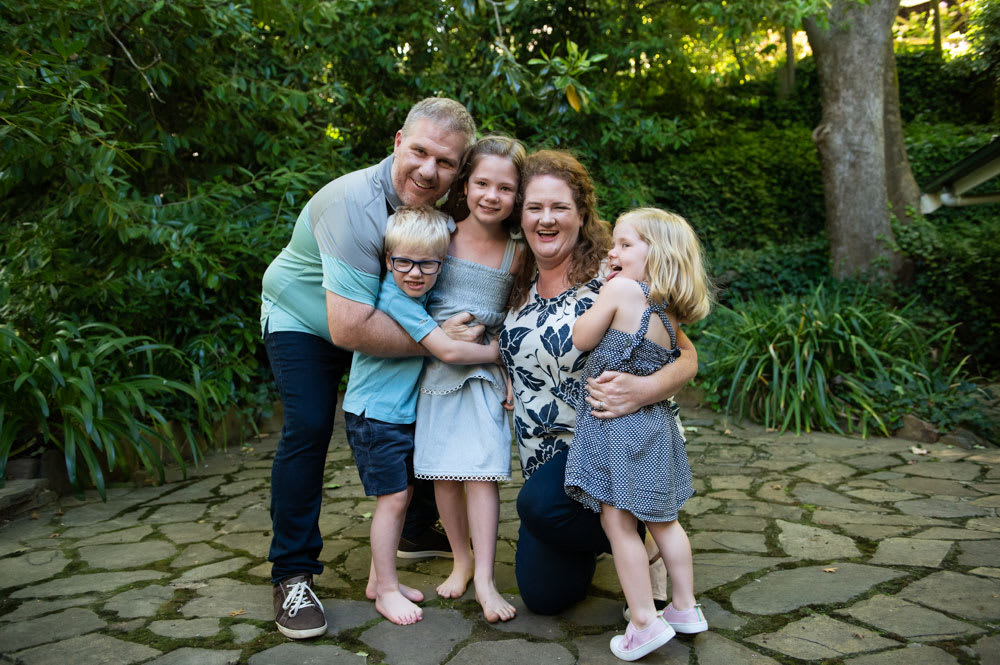 MyBudget clients Pete and Alyssa with three young children in a beautiful green garden - how to stress less about money