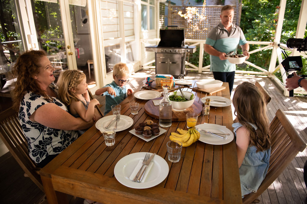 MyBudget clients Pete and Alyssa with three young children sitting outside enjoying lunch - how to stress less about money