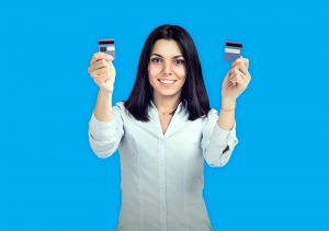 A woman in a white shirt holding up two blue credit cards