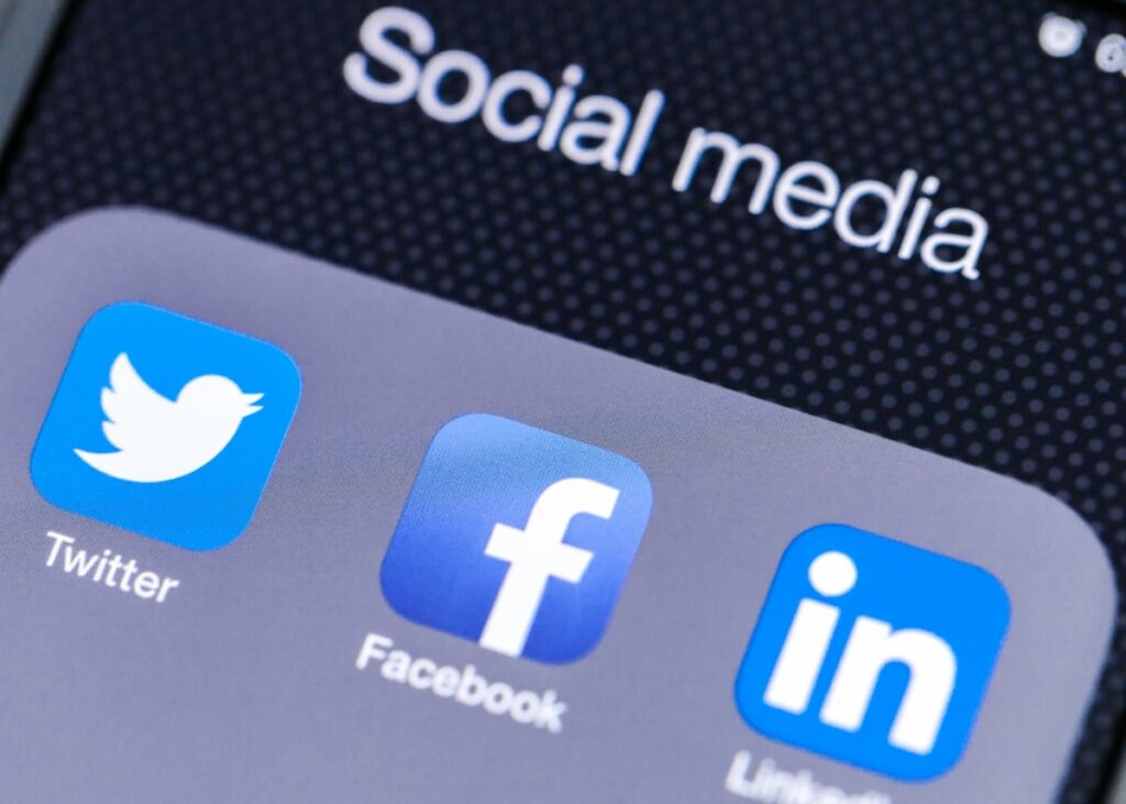 A phone screen with the social media folder open showing the twitter, facebook and linkedin apps