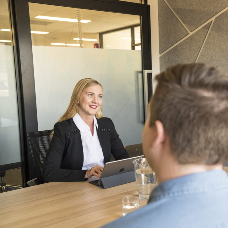 White woman in her thirties in a conference room smiling at clients.