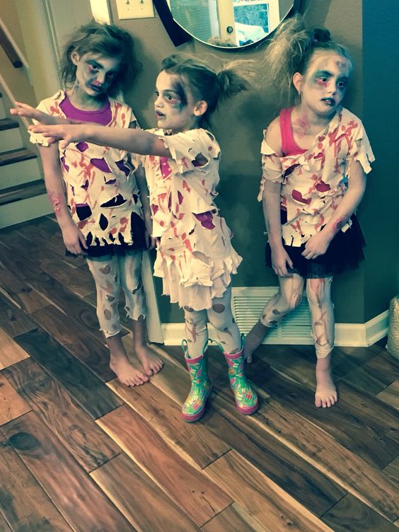 Three young girls dressed in tattered rags with makeup on acting like zombies as cheap halloween costumes ideas