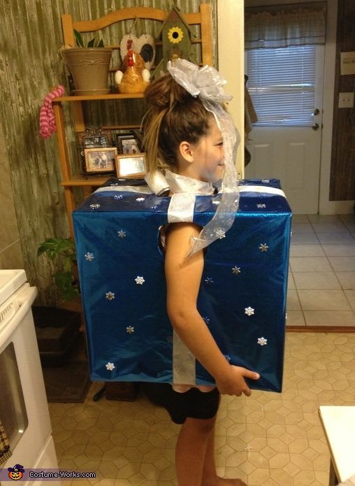 A young girl wearing a boxed present with a bow on her head as cheap halloween costumes ideas