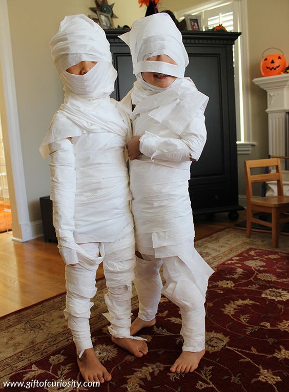 Two children wrapped in toilet paper dressed as Egyptian mummies as a low cost halloween costume