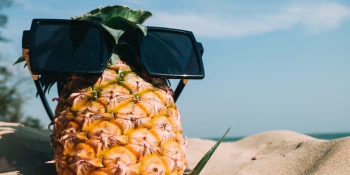 A pineapple wearing sunglasses on the beach - Cheap Mother’s Day gifts