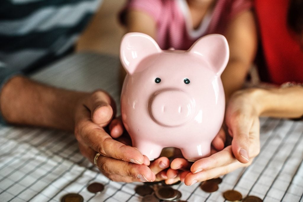 A piggy bank being held by a man, woman and child.