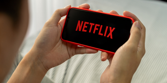 A person holding a mobile phone with the Netflix logo