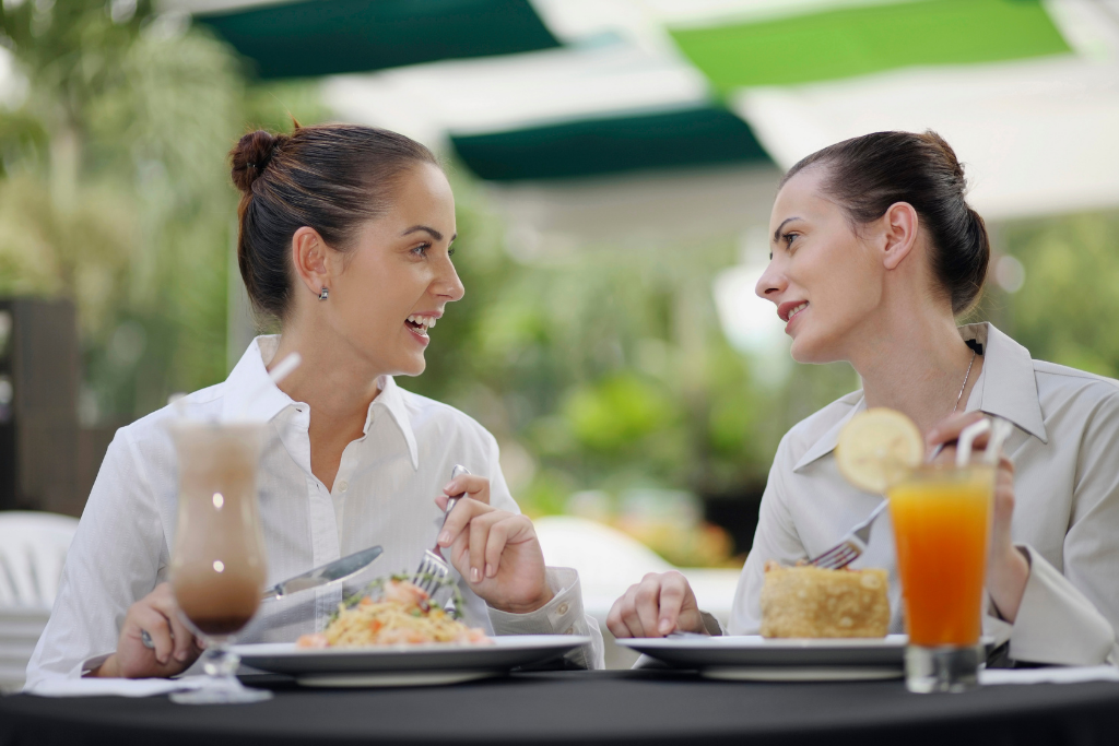 Two young women sitting over lunch talking to each other