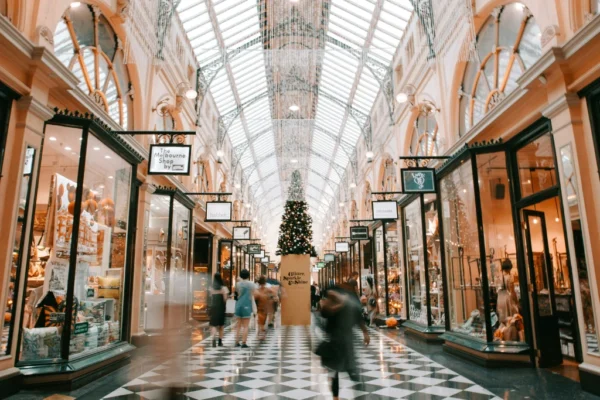 A decorated shopping arcade bustling with people, featuring a Christmas tree at its centre> Learn how to create a Christmas budget in Australia with MyBudget.