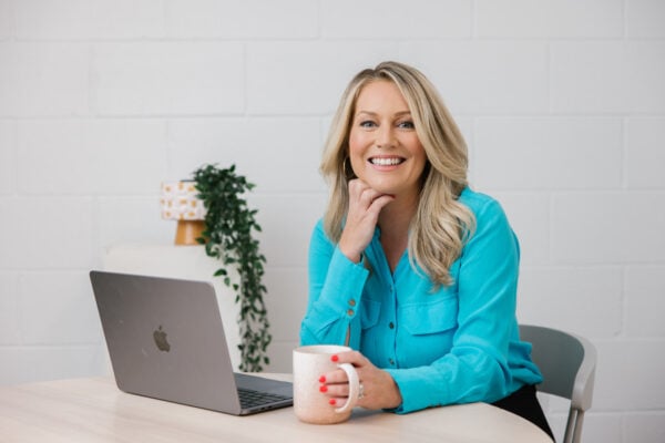 Tammy Barton, Founder of MyBudget, at her desk with a laptop and mug, sharing expert tips on saving money on household bills.