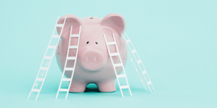 A piggy bank with four white ladders around it.